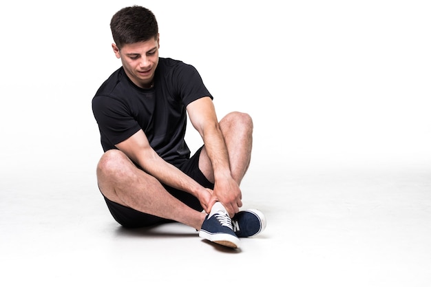 Portrait of athlete man suffering from pain in leg isolated on a white 