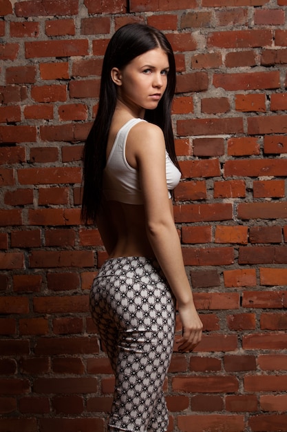 Portrait of athletic brunette on brick wall