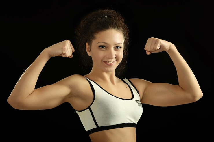 Photo portrait of athletic girl shows biceps on a black background