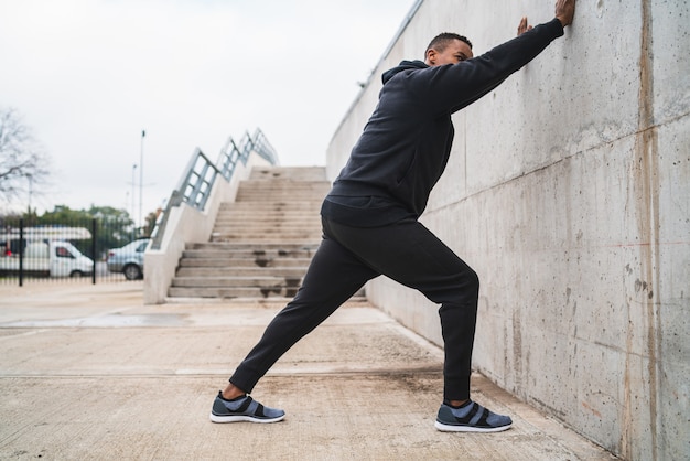 Portrait of an athletic man stretching legs before exercise outdoors. Sport and healthy lifestyle.