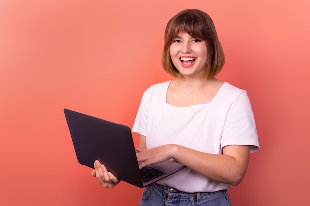 Portrait attractive amazed cheerful girl agent broker using laptop having fun pink color background