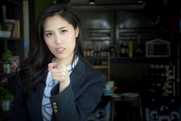 Portrait of attractive Asian businesswoman in a suit pointing her finger to you