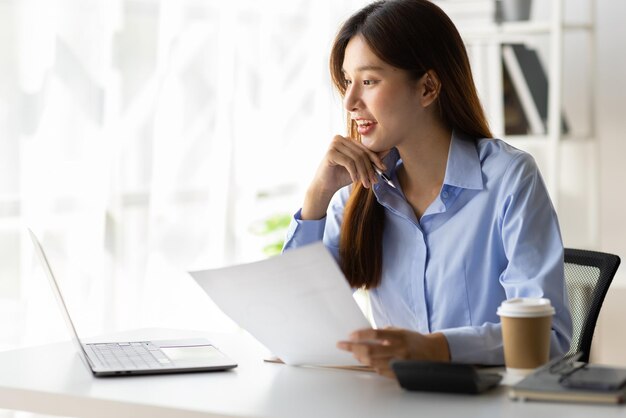 Photo portrait of attractive asian businesswoman working with laptop and documents in office