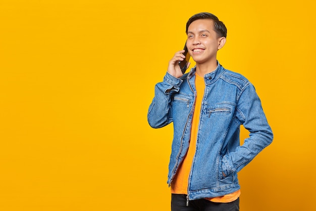 Portrait of attractive asian man talking on smartphone and looking happy