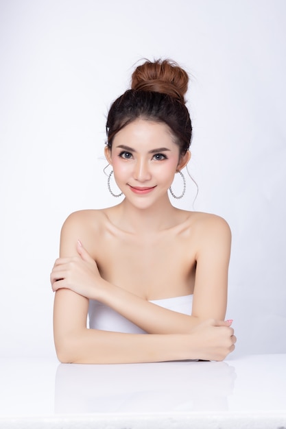 Photo portrait of attractive asian woman sitting smiling on white background.