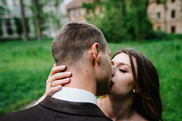 Ritratto di un'attraente sposa posteriore che abbraccia e bacia lo sposo.