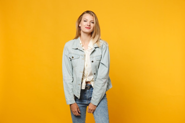 Foto ritratto di giovane e bella donna attraente in abiti casual denim in piedi, guardando la fotocamera isolata su sfondo muro giallo arancione brillante in studio. concetto di stile di vita delle persone. mock up spazio di copia.