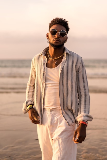 Portrait of attractive black ethnic man enjoying summer vacation by the sea at sunset