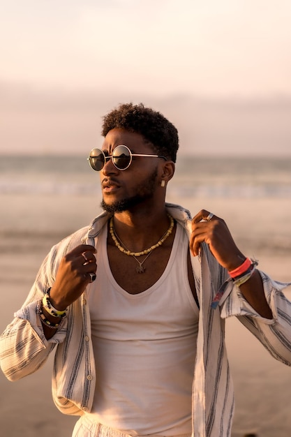 Portrait of attractive black ethnic man enjoying summer vacation by the sea at sunset