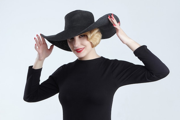 Photo portrait of an attractive blonde with a retro hairstyle in a black hat with a wide brim