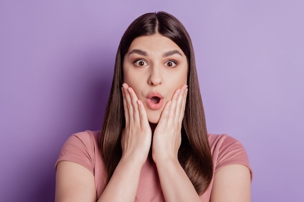 Portrait of attractive brunette girl opened mouth palms holding cheeks shocked fake news isolated over violet background