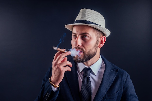 Foto ritratto di un uomo d'affari attraente con un sigaro in studio di sfondo nero