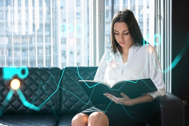 Portrait of attractive businesswoman in formal wear working with documents and thinking how to optimize IPO strategy Financial chart hologram over modern office background Go public concept