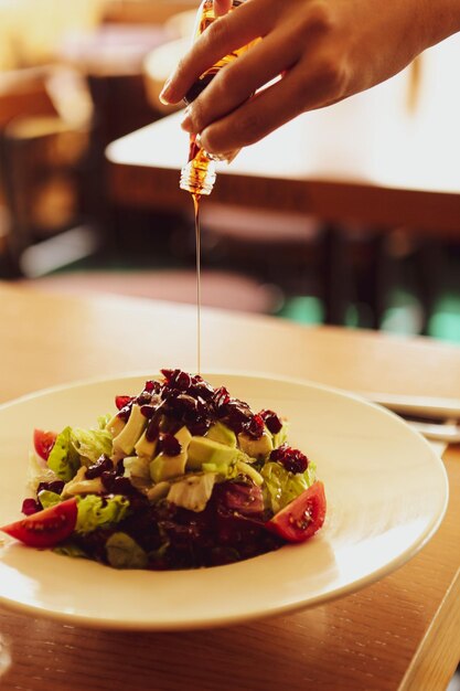 Portrait of attractive caucasian smiling woman eating salad focus on hand and fork