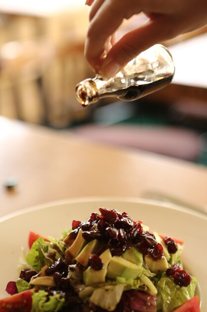 Portrait of attractive caucasian smiling woman eating salad focus on hand and fork