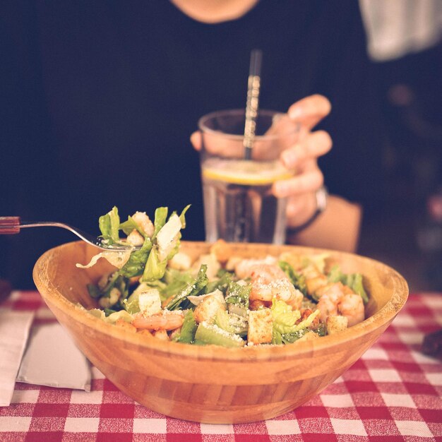 Portrait of attractive caucasian smiling woman eating salad focus on hand and fork