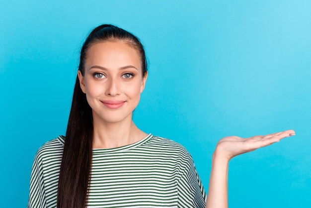 Portrait of attractive charming cheerful girl holding palm empty place space isolated over bright shine blue color background