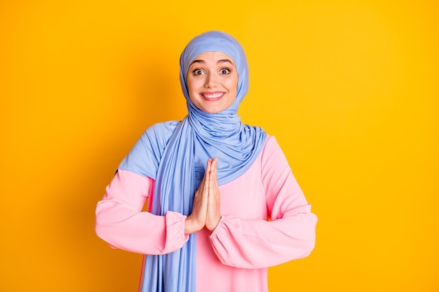 Portrait of attractive cheerful cheery muslimah wearing hijab asking favor gift surprise isolated on bright yellow color background