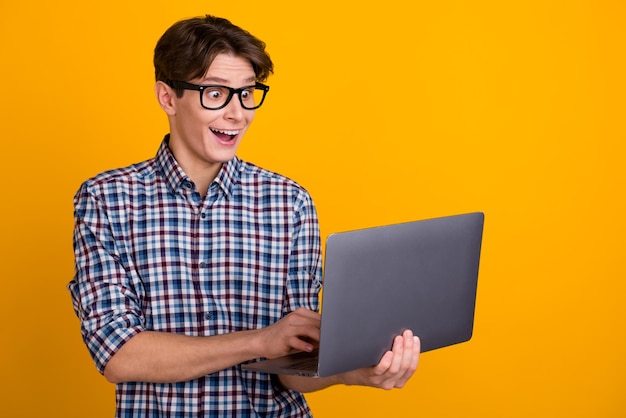 Portrait of attractive cheerful successful smart brunet guy broker hold laptop work isolated over bright color background