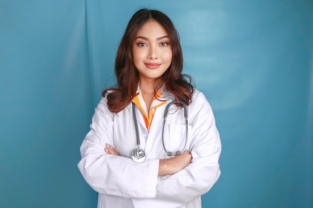 Portrait of an attractive confident female doctor friendly smiling arms crossed wear white lab coat stethoscope isolated blue color background