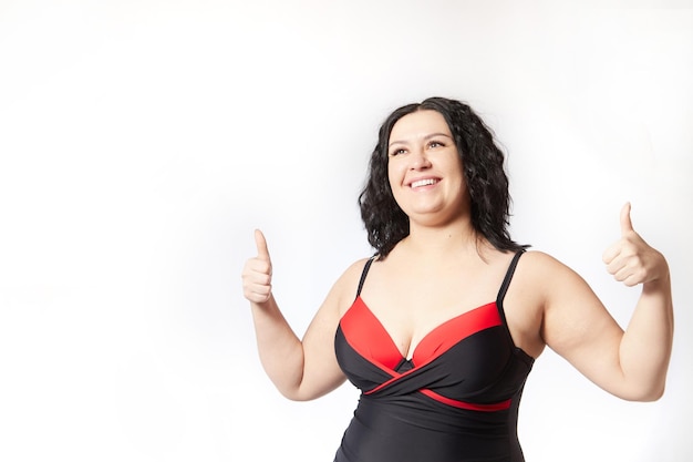 Foto ritratto di una donna attraente e sognante in costume da bagno rosso e nero che posa su un corpo bianco