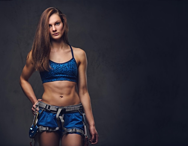 Portrait of attractive female free climber with protective gear over grey background.