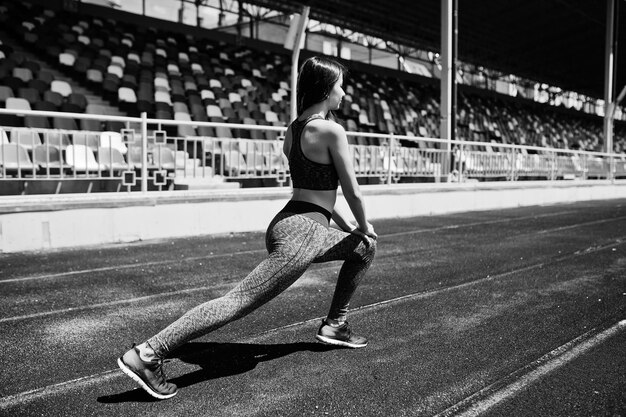 Photo portrait of an attractive fit woman doing exercises for her legs in the stadium black and white photo