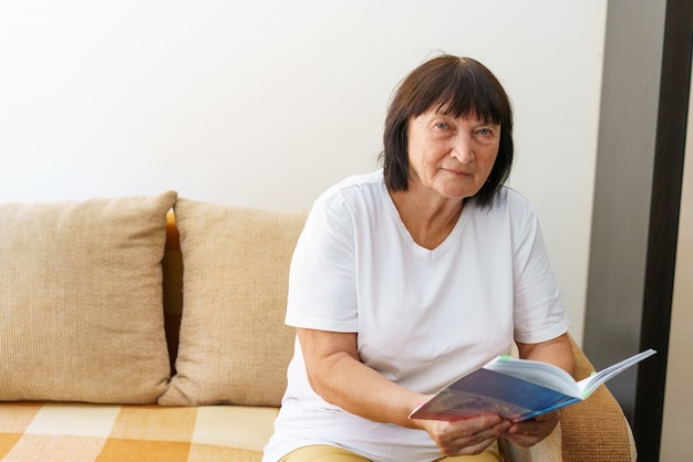 Portrait of attractive focused cheerful woman sitting on sofa reading book pastime dream at home hom...