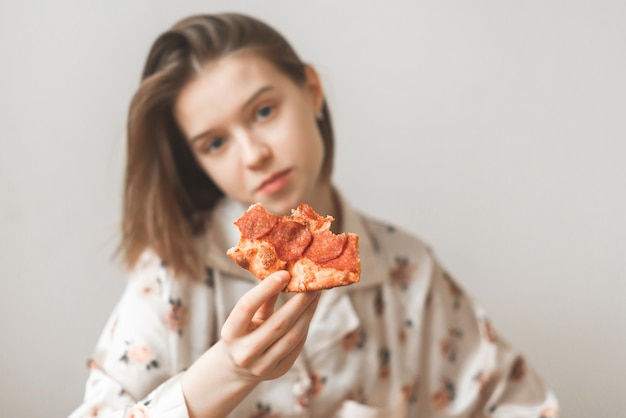 Portrait of an attractive girl holding a piece of pizza in her hands