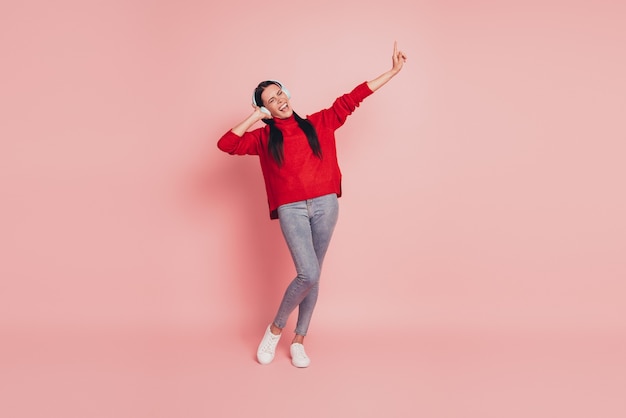 Portrait of attractive girlish girl listening hit song isolated on pink color background