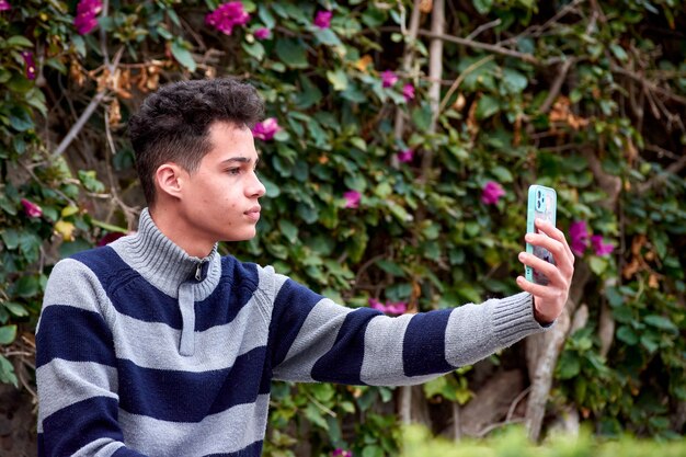 A portrait of an attractive Hispanic male taking a selfie in the park