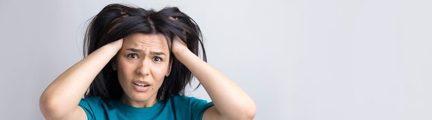 Portrait of attractive lady holding hands on head. Human face expressions and emotions.