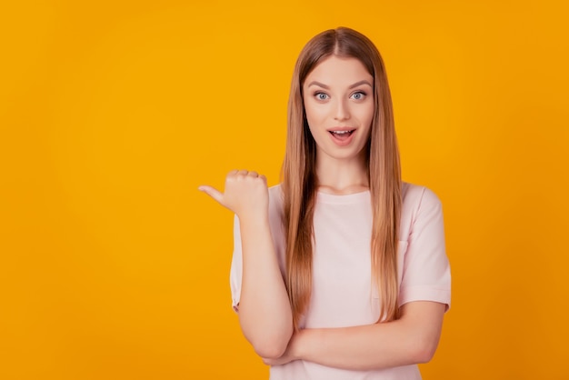 Portrait of attractive lady thumb direct side open mouth funny reaction show blank space on yellow background