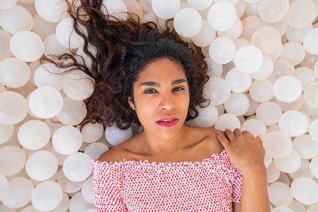 Portrait of an attractive latin girl lying on plastic balls she has an intense look is pretty