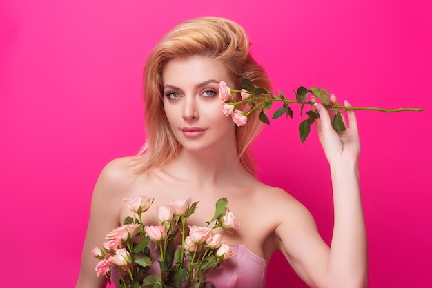 Portrait of attractive lovely charming dreamy girl holding pink roses isolated on pink studio backgr