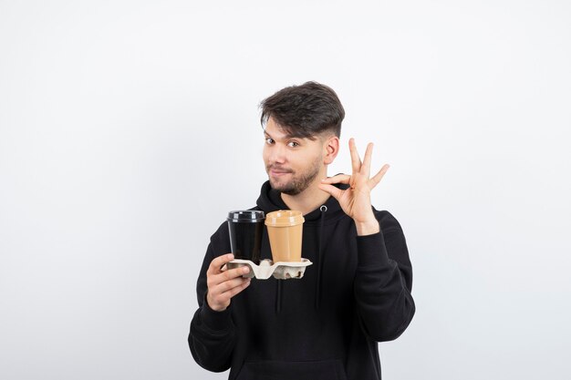 Portrait of attractive man holding two take-away cups in a carton 