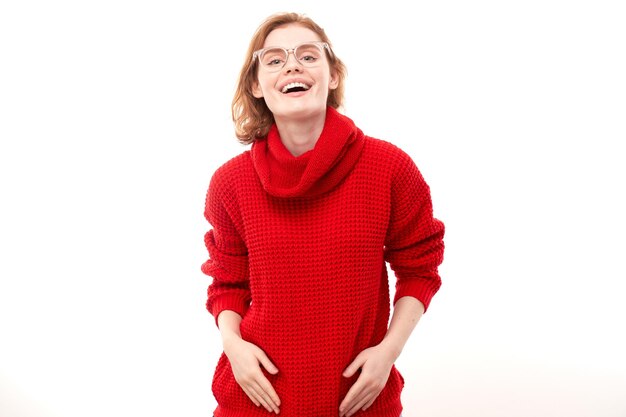 Portrait of attractive redhaired girl in red Christmas sweater smiling joyfully isolated on white studio background