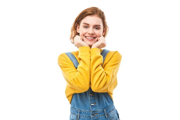 Portrait of attractive redhaired girl in yellow casual smiling joyfully isolated on white studio background