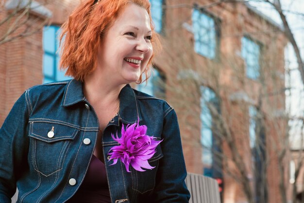 Portrait of an attractive redhaired woman in sunglasses and a denim jacket with a bright brooch