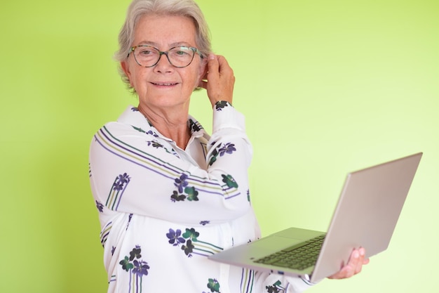 Photo portrait of attractive senior business woman holding laptop in hand isolated on green background