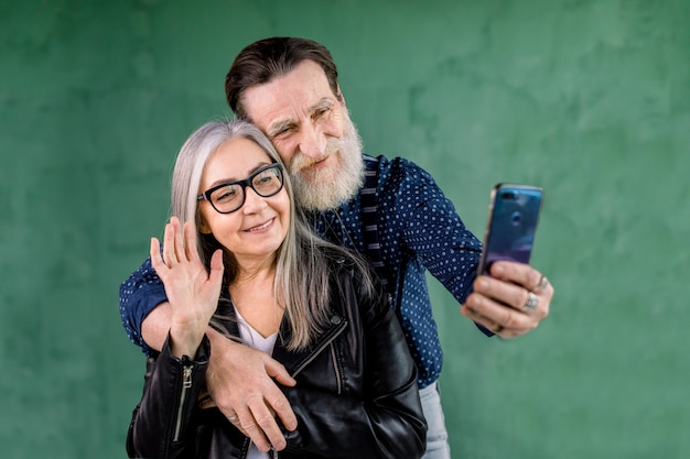 Portrait of attractive senior couple, standing at home in front of green wall 