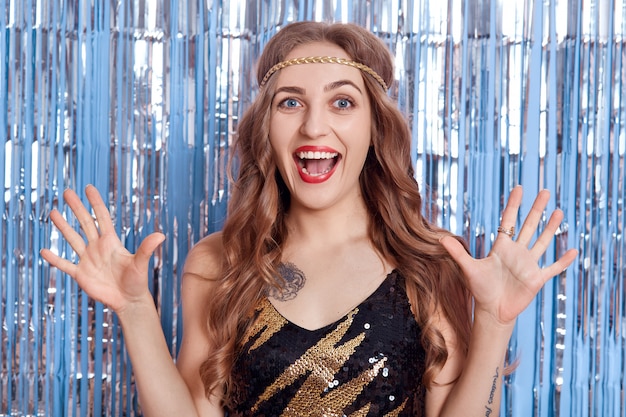 Portrait of attractive smile girl raised up her arms, dresses black outfit, laughing happily and keeps mouth widely opened