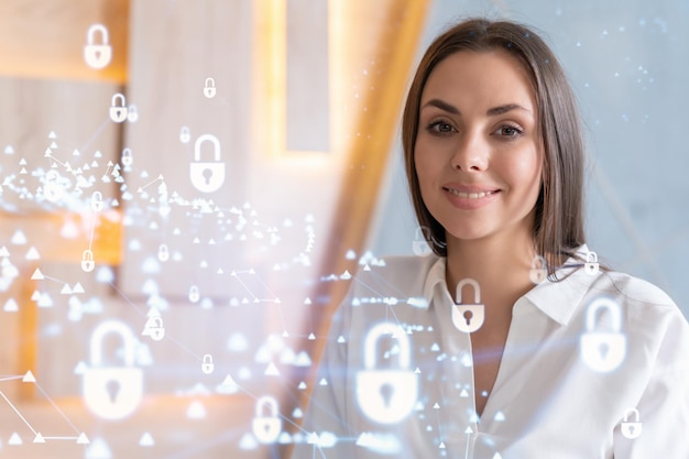 Portrait of attractive smiling businesswoman thinking how to protect clients confidential information and cyber security IT hologram padlock icons over office background