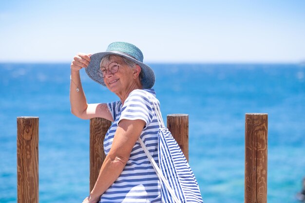 Portrait of attractive smiling caucasian senior woman sitting outdoors at sea enjoying summer holidays Horizon over water