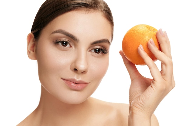 Portrait of attractive smiling woman isolated on white studio shot eating orange