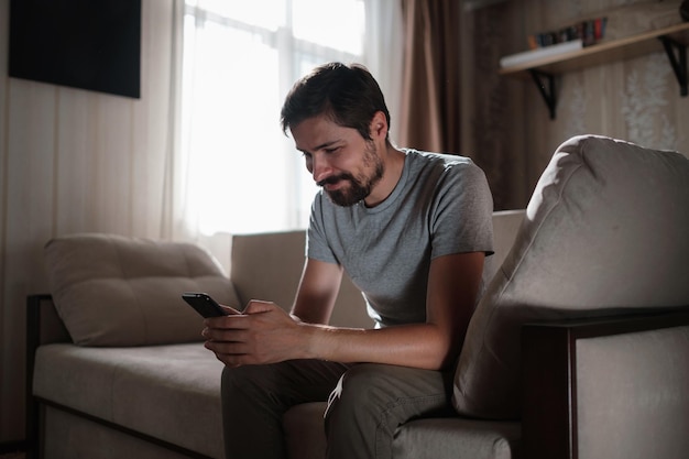 Portrait of an attractive smiling young bearded man wearing casual clothes sitting on a couch