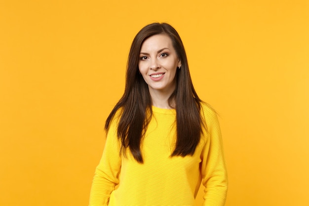 Portrait of attractive smiling young woman in casual clothes looking camera isolated on bright yellow orange wall background in studio. people sincere emotions, lifestyle concept. mock up copy space