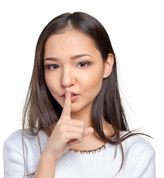 Portrait of attractive teenage girl with finger on lips