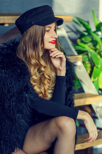 Portrait of attractive woman in a black cap and a coat with a fur collar