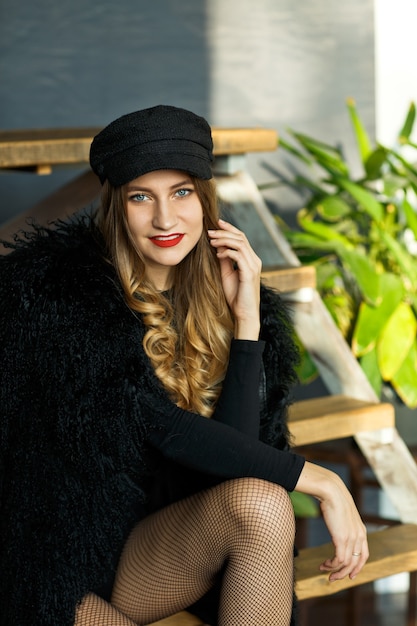 Portrait of attractive woman in a black cap and a coat with a fur collar